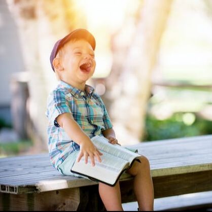 Small boy with a Bible, laughing. Photo by Ben White, Unsplash.